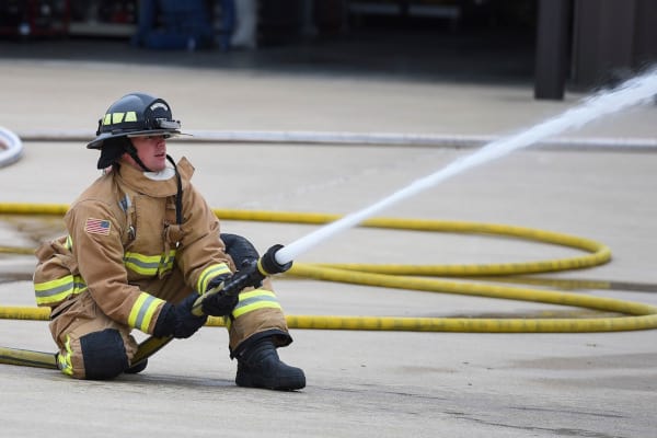 A single firefighter spraying water from a fire hose