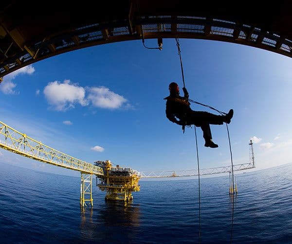 Man hanging from an oil rig