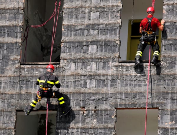 Firefighters hanging from rope