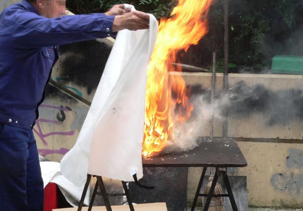 A fire blanket being used to smother a fire